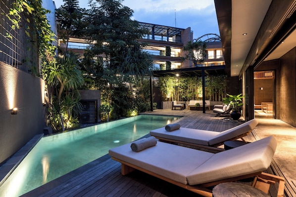 A modern outdoor pool area with lounge chairs and a wooden deck.
