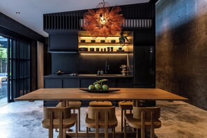 A modern kitchen with a wooden dining table and chairs, a hanging light fixture, and a built-in oven.