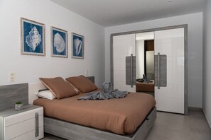 Ein modernes Schlafzimmer mit einem Bett, Nachttischen, einer Kommode und einem großen Spiegel.