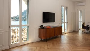Ein geräumiger Wohnbereich mit einem großen Flachbildfernseher an der Wand, einer Holzkassette und einem Esstisch mit Stühlen.