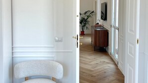 Ein Flur mit einer weißen Tür, einem runden Hocker, einem Blumentopf und einem Holzschrank.