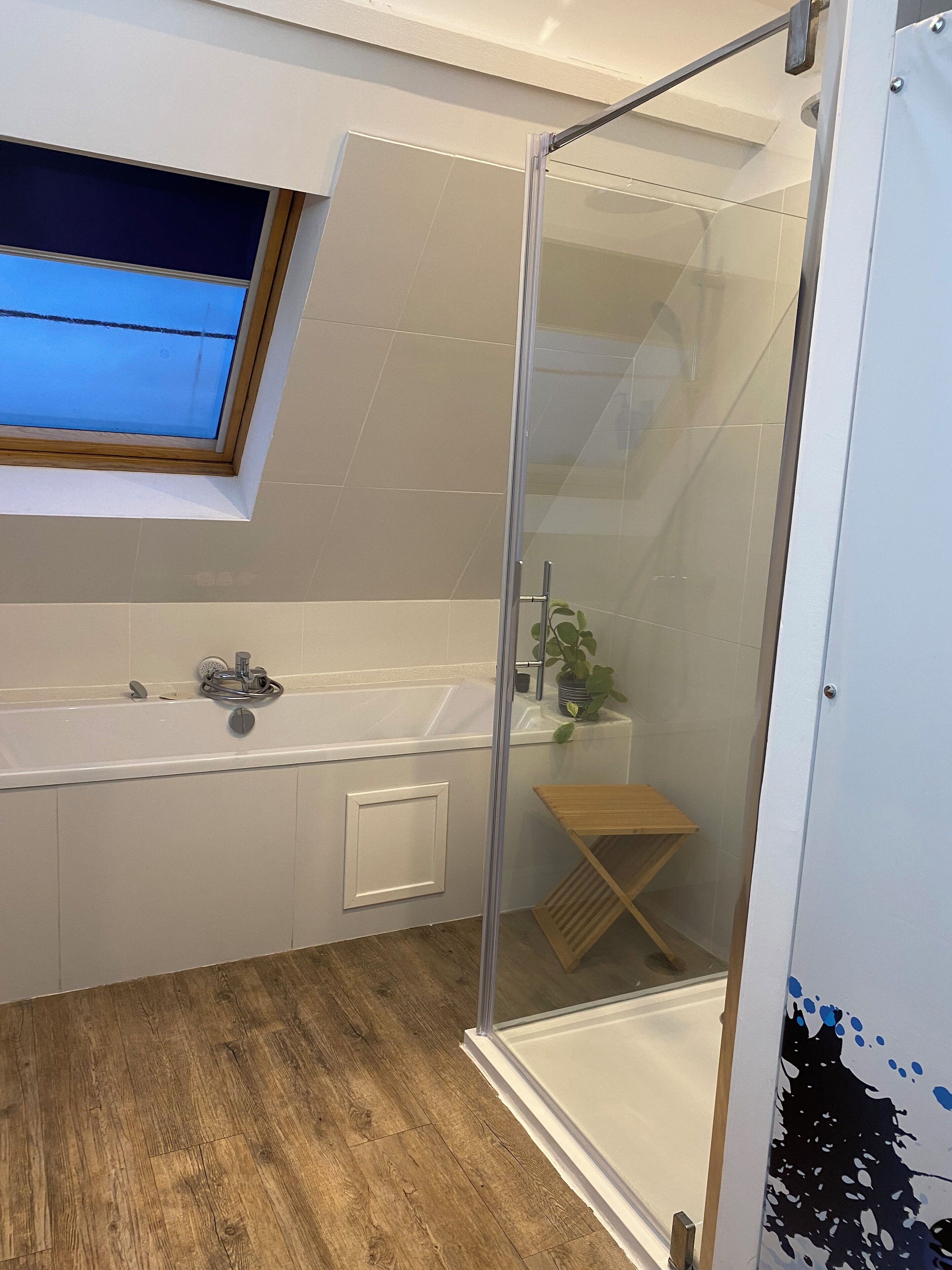 Une salle de bain moderne avec une douche à parois de verre, une fenêtre intégrée au-dessus du lavabo et un plancher en bois.