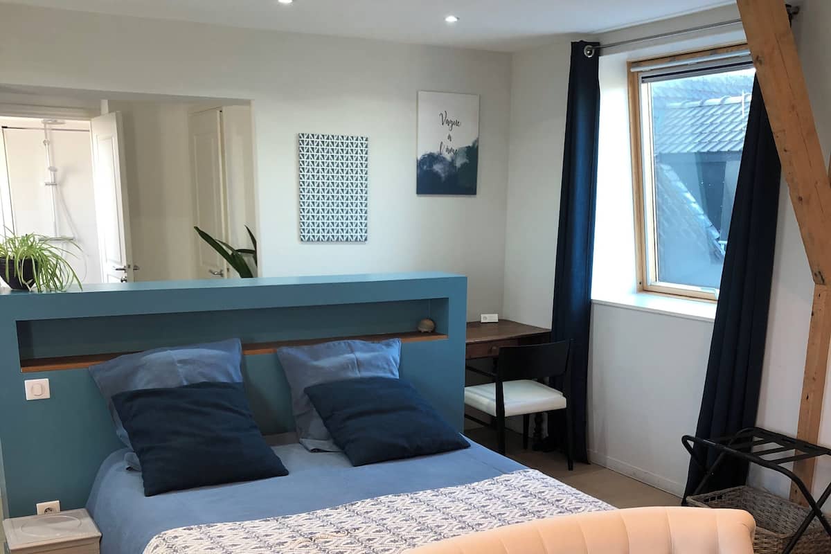 Un dormitorio con cama, una silla, un escritorio y una ventana.