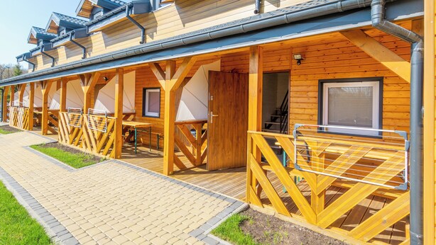 Una fila di chalet in legno con sedute esterne e una passerella coperta.