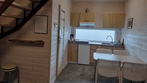 Una cucina compatta con pareti in legno, un piano cottura integrato, un lavello e un piccolo spazio pranzo con due sedie.