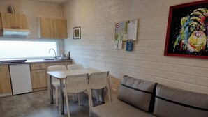 Una cucina compatta con mobili in legno, un piano di lavoro bianco e un'area pranzo con tavolo e sedie.