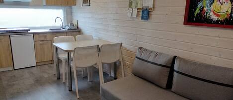 A compact kitchen with wooden cabinets, a white countertop, and a dining area with a table and chairs.
