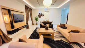 Una sala de estar moderna con televisor de pantalla plana, sofás, una mesa de centro y un tapete decorativo.
