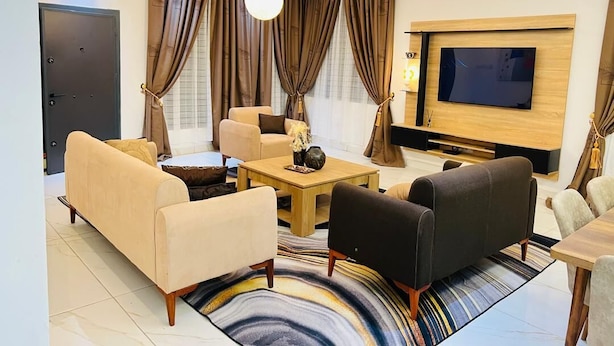 Una sala moderna con un sofá, sillones, una mesa de centro y un televisor.