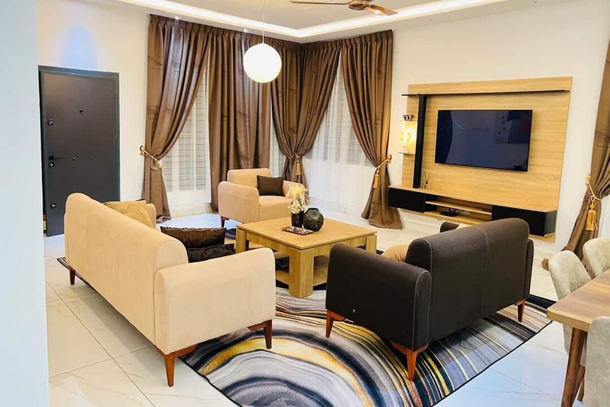 Una sala moderna con un sofá, sillones, una mesa de centro y un televisor.