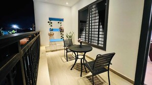 Un balcón con mesa y sillas, un muro decorativo y una ventana con diseño de cuadrícula.