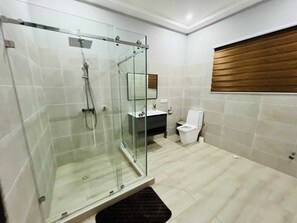 Un baño moderno con ducha de vidrio, inodoro, lavamanos y espejo con marco de madera.