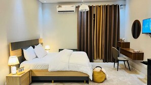 Habitación de hotel moderna con una cama grande, mesitas de noche, un escritorio y un televisor.