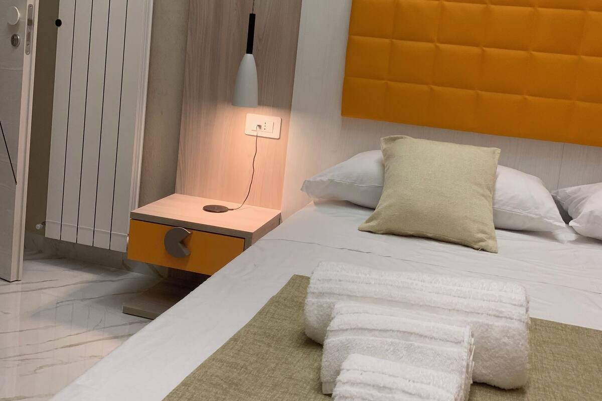 Une chambre d’hôtel moderne équipée d’un lit, d’une table de chevet, d’une lampe et d’un radiateur.
