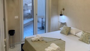 A bedroom with a bed, a bedside table with a lamp, a sliding glass door to an outdoor balcony, and a TV mounted on the wall. - Santa Ciriaca - Aghìa Kyriaki (Gerace)