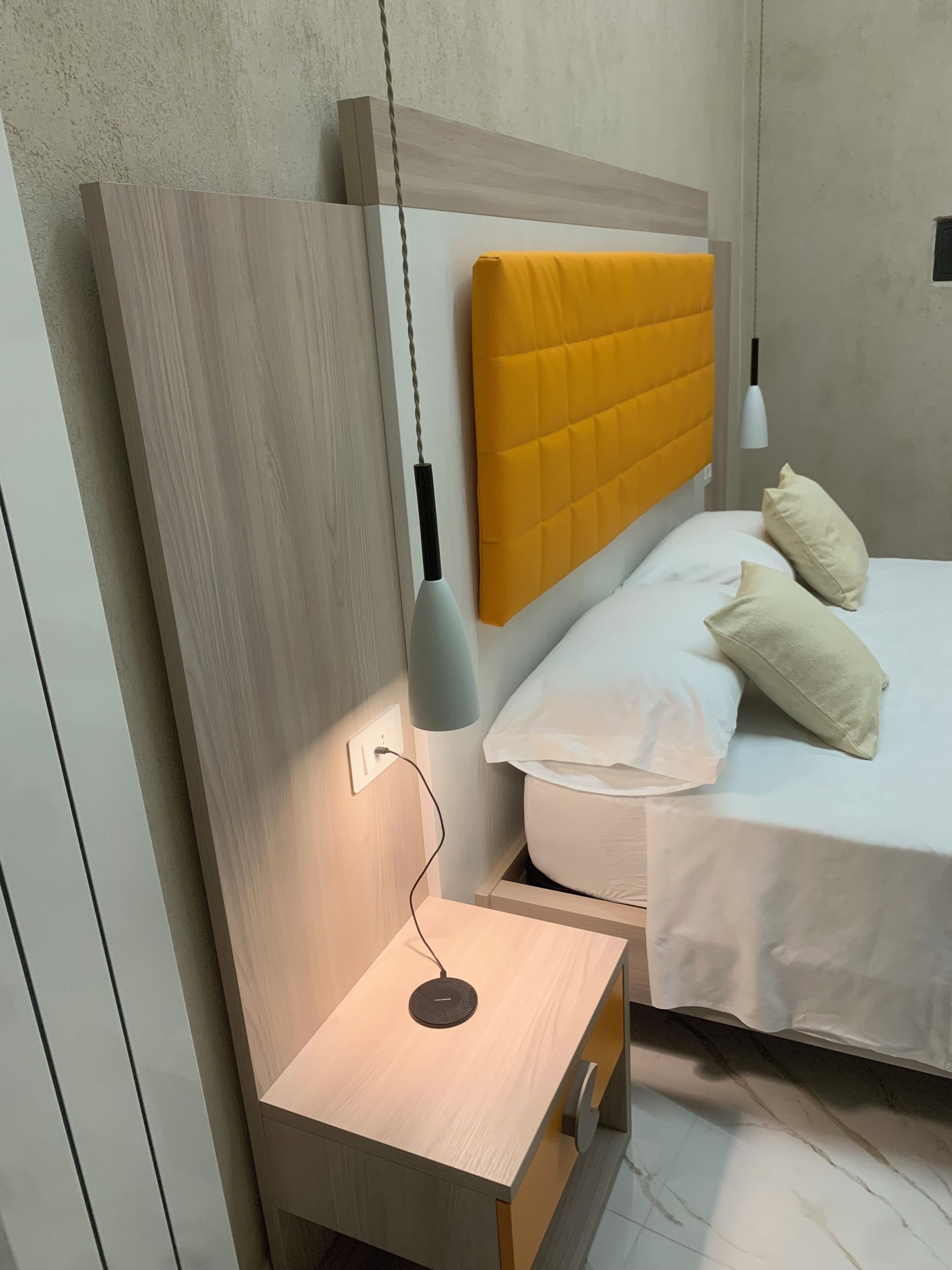 A modern bedroom with a wooden headboard, bedside table, and a lamp.