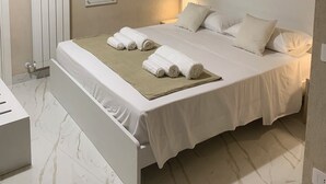 A bedroom with a bed, pillows, a bedside table, a mirror, and a radiator. - Santa Ciriaca - Aghìa Kyriaki (Gerace)