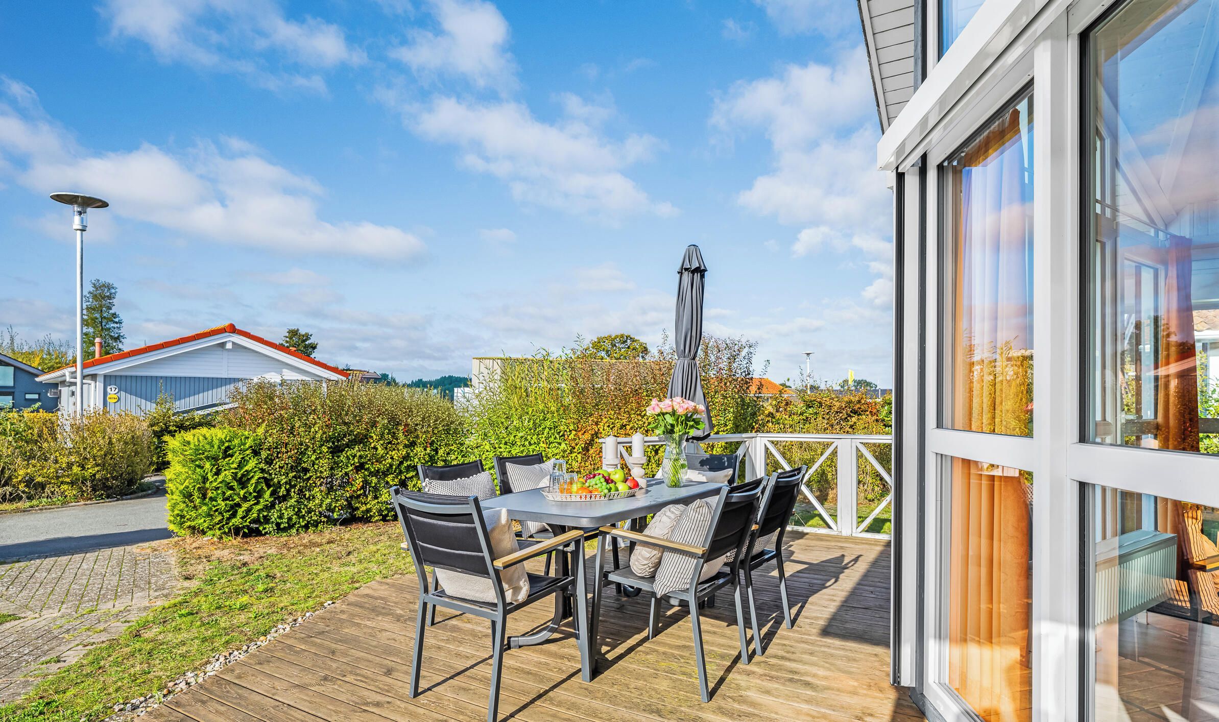 En terrasse med et bord, stole, en lampe og udsigt over det omkringliggende område.