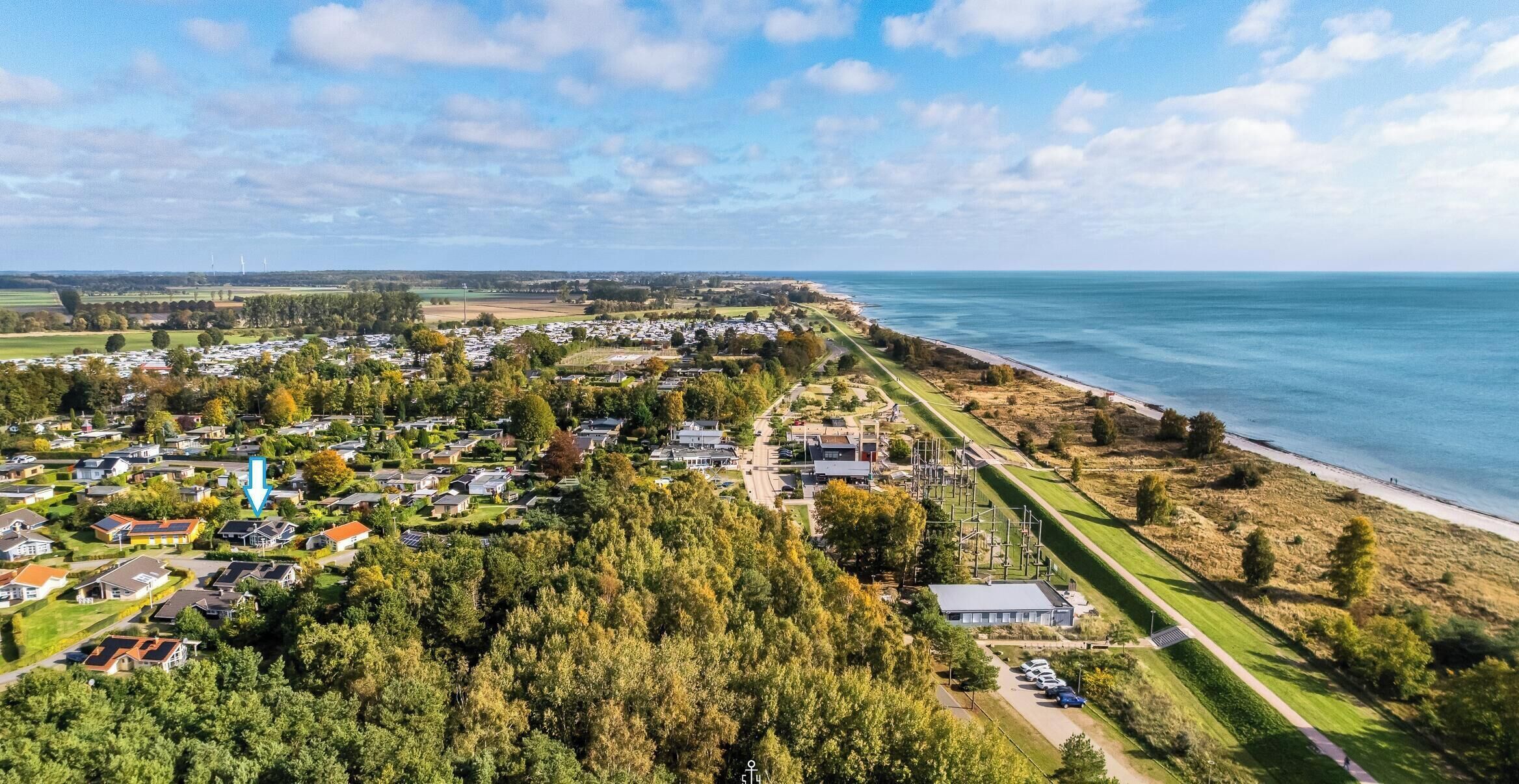 Et kystnære boligområde med huse, strand og lysthavn.