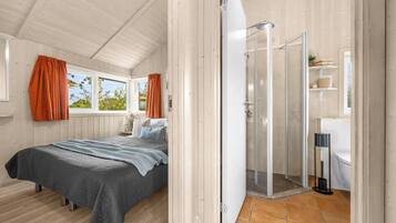 A bedroom with a bed, a shower, and a bathroom.