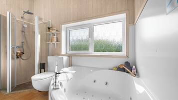 Ein modernes Badezimmer mit einer großen Badewanne, einer Duschkabine und einer Toilette.