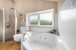 A modern bathroom with a large bathtub, a shower enclosure, and a toilet.
