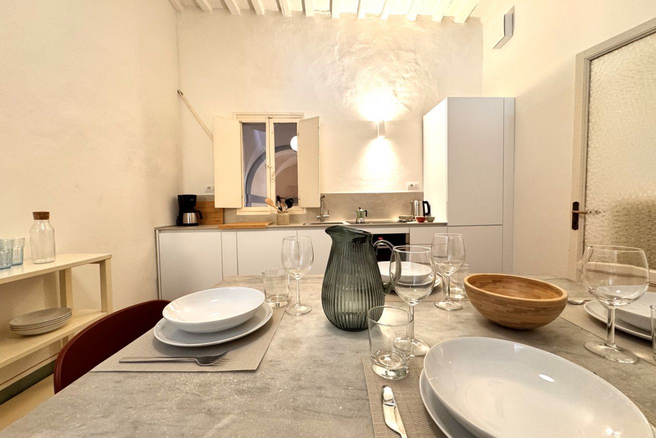 Una cocina moderna con alacenas blancas, horno empotrado y una ventana sobre el fregadero.