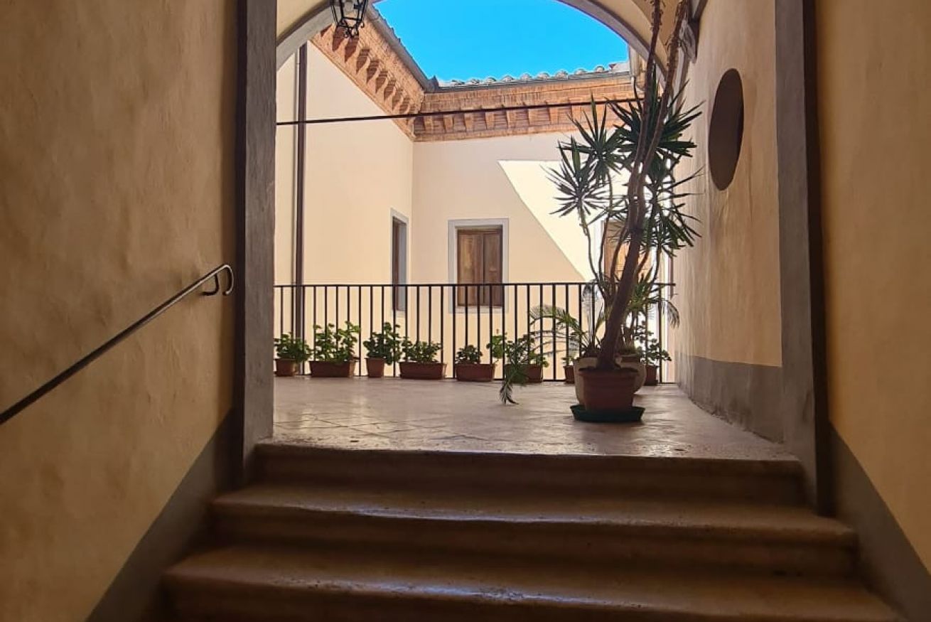 A staircase leading to a courtyard with potted plants and a tiled roof.