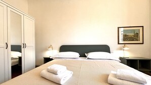 Ett hotellrum med en stor säng, två sängbord med lampor, en garderob och en inramad tavla på väggen.