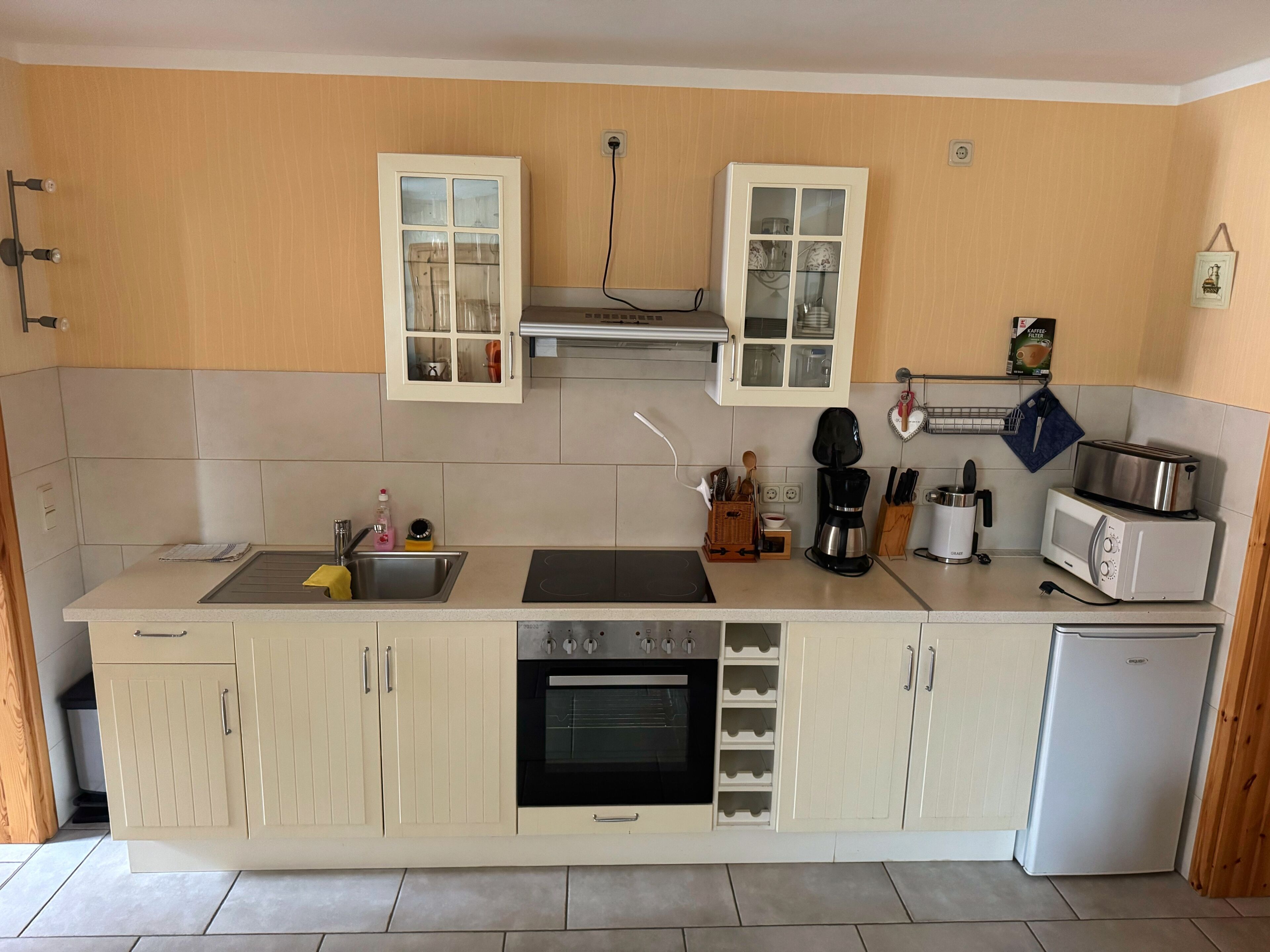 A kitchen with a sink, stove, oven, microwave, and cabinets.
