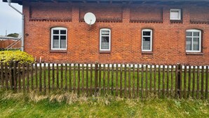 Un bâtiment en briques, doté d’une antenne parabolique, de trois fenêtres et d’une clôture en bois.