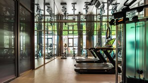 Een fitnessruimte met loopbanden, krachtapparaten en een groot raam met uitzicht op het landschap.