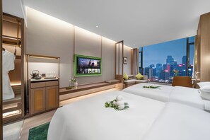 Quarto de hotel com duas camas, televisão, vista para a cidade e guarda-roupa de madeira.