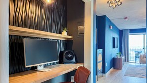 A modern room with a wooden desk, a computer monitor, a fan, and a leather chair. - City Views~Close 2 Salem~Balcony (Beverly)