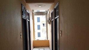 Un corridoio stretto con pavimento piastrellato, che conduce all'ingresso di un edificio.