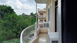 Un balcone con ringhiera curva, soffitto bianco e vista su un paesaggio verde e edifici in lontananza.