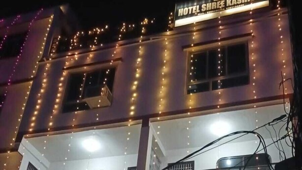 Un edificio a più piani con luci a stringa illuminate e un cartello con su scritto "HOTEL SHREE KASHI INN".