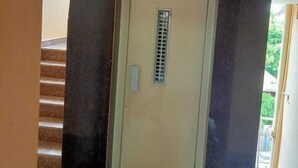 Un corridoio con una porta, una griglia di aerazione e una scala.