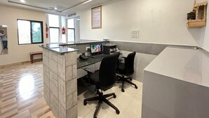 A reception area with a counter, two black office chairs, a computer, and a reception desk.