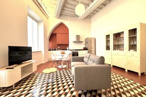 A modern living room with a sofa, TV, and dining area. - Casa Bruna - Via Banchi di Sotto (Siena)