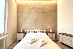 A bedroom with a large bed, two bedside tables, and a dresser. - Casa Bruna - Via Banchi di Sotto (Siena)