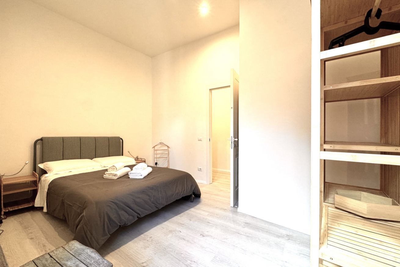 A bedroom with a bed, bedside table, and a wardrobe.