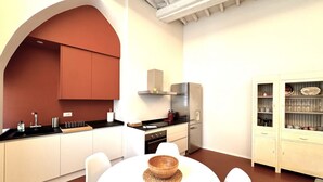 A modern kitchen with white cabinets, a black countertop, and a stainless steel range hood. - Casa Bruna- Via banchi di sotto (Siena)