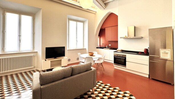 A modern apartment with a living room, dining area, kitchen, and a large window. - Casa Bruna- Via banchi di sotto (Siena)