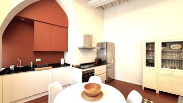 A modern kitchen with white cabinets, a black countertop, and a stainless steel range hood.