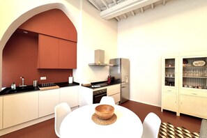 A modern kitchen with white cabinets, a black countertop, and a stainless steel range hood. - Casa Bruna - Via Banchi di Sotto (Siena)