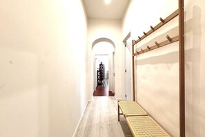 A hallway with a wooden bench, a coat rack, and an arched doorway leading to another room.