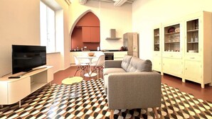 A modern living room with a sofa, TV, and dining area. - Casa Bruna- Via banchi di sotto (Siena)