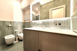 A modern bathroom with a toilet, sink, and mirror. - Casa Bruna - Via Banchi di Sotto (Siena)