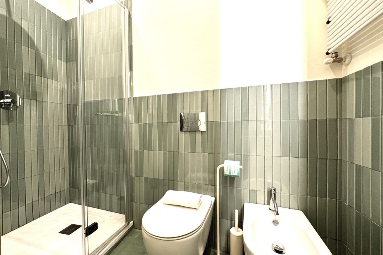 Un bagno con doccia vetro, un water e un lavandino.